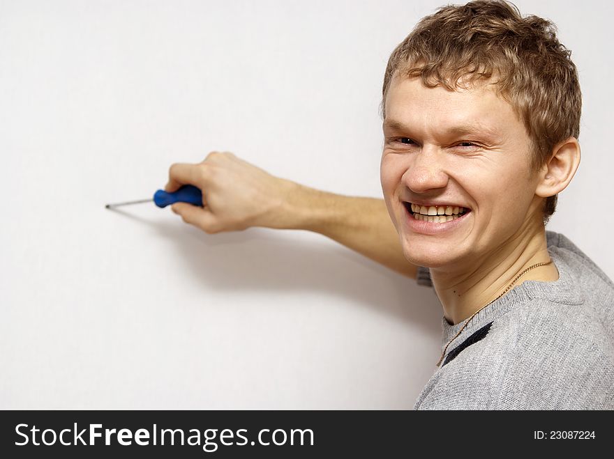 The gray background of the boy holds in his hands a screwdriver. The gray background of the boy holds in his hands a screwdriver