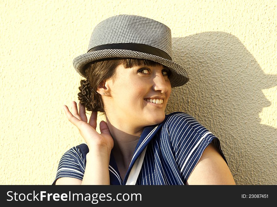 Near the wall happy brunette girl with hat