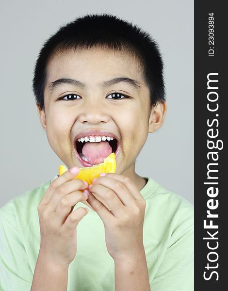 A little boy enjoying himself eating a slice of orange. A little boy enjoying himself eating a slice of orange