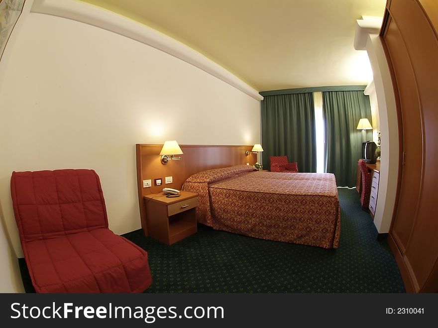 An empty hotel room, with a bed and two lamps on the nightstands and a semi open window like generic looking hotel room