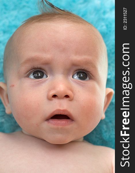 Image of beautiful 6 month old baby boy lying on a fuzzy turquoise blanket. Image of beautiful 6 month old baby boy lying on a fuzzy turquoise blanket