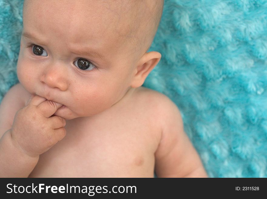 Image of beautiful 6 month old baby boy lying on a fuzzy turquoise blanket. Image of beautiful 6 month old baby boy lying on a fuzzy turquoise blanket