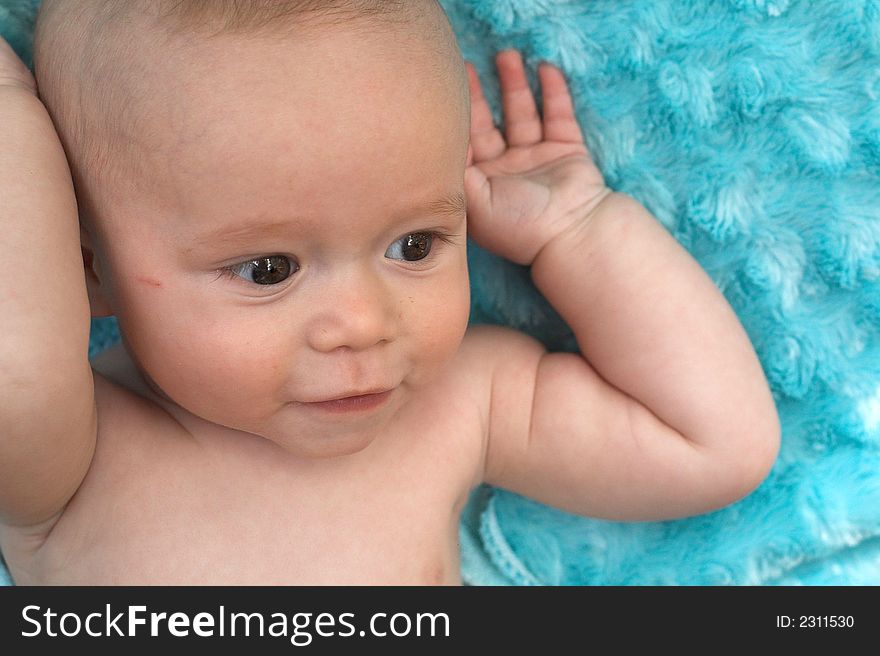 Image of beautiful 6 month old baby boy lying on a fuzzy turquoise blanket. Image of beautiful 6 month old baby boy lying on a fuzzy turquoise blanket