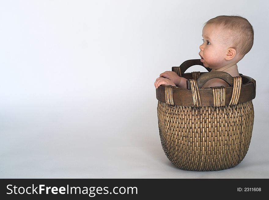 Image of cute baby sitting in a woven basket. Image of cute baby sitting in a woven basket
