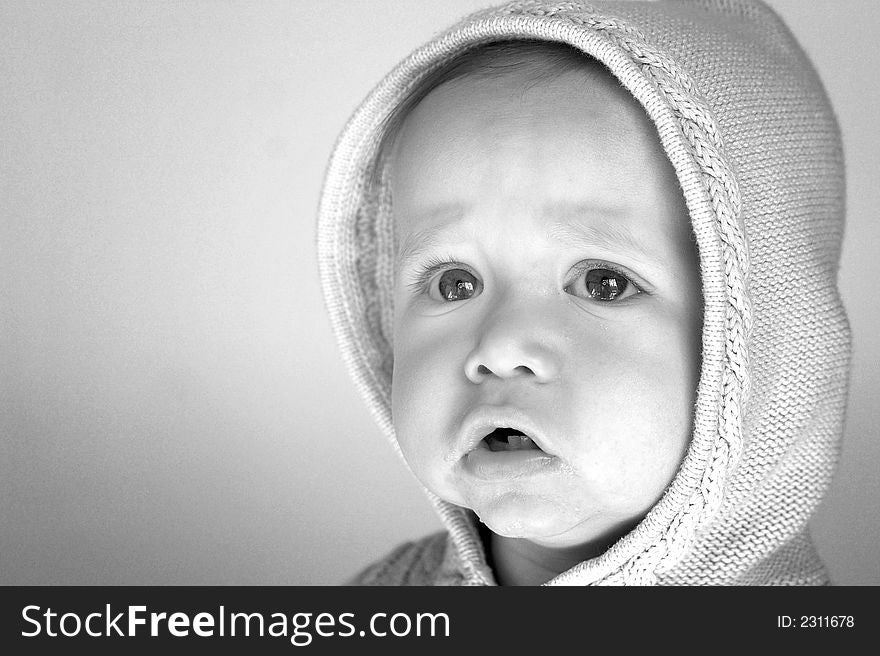 Black and white image of cute baby wearing a hooded sweater. Black and white image of cute baby wearing a hooded sweater