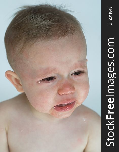 Image of crying baby sitting in front of a white background