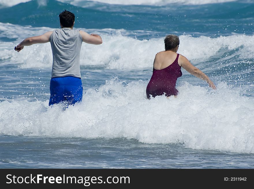 Two people walking into the surf and waves on a Florida beach. Two people walking into the surf and waves on a Florida beach