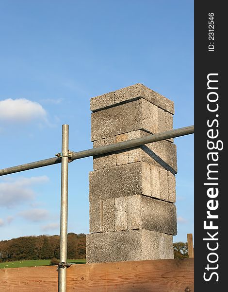 Concrete blocks stacked on scaffolding against a blue sky.