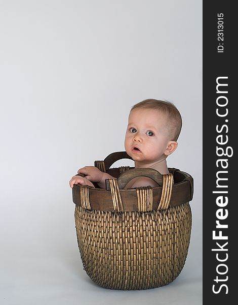 Image of cute baby sitting in a woven basket. Image of cute baby sitting in a woven basket