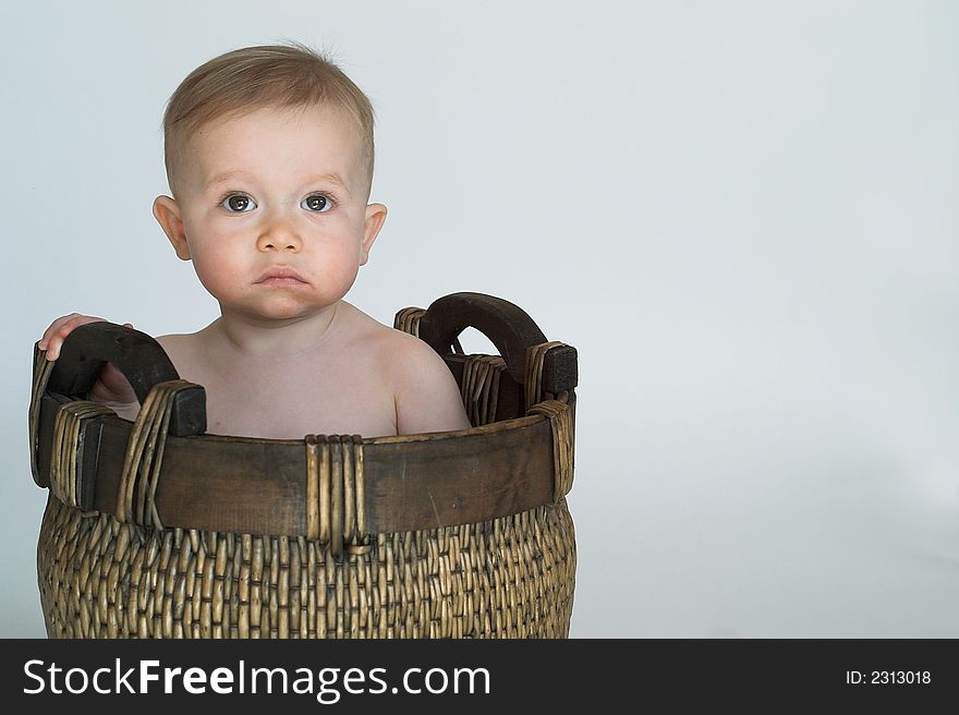 Image of cute baby sitting in a woven basket. Image of cute baby sitting in a woven basket