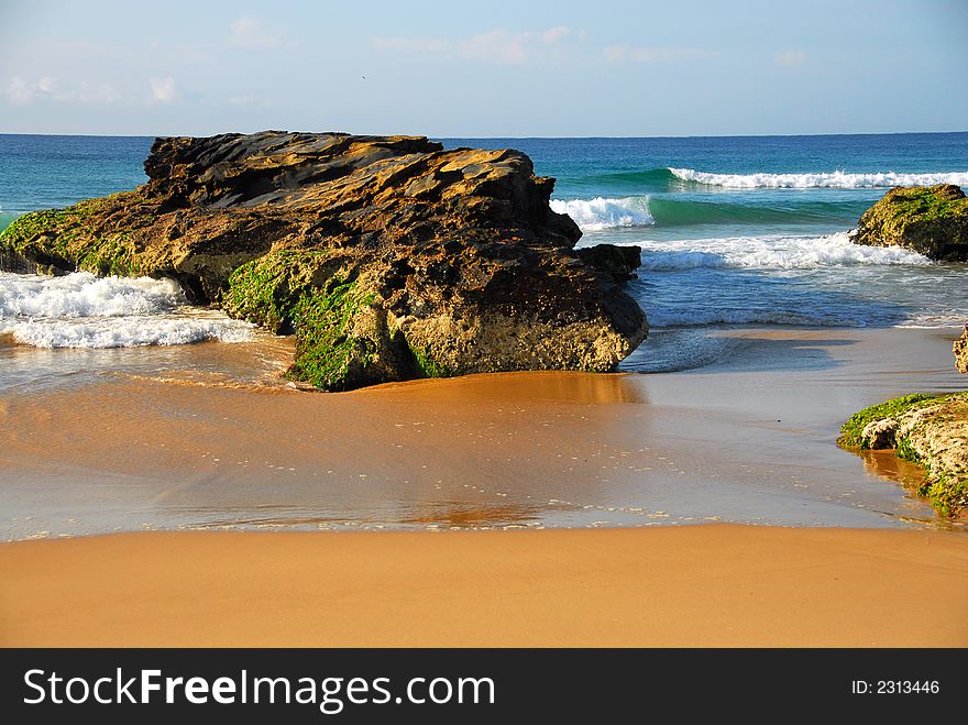 Waves rolling into the shore around a large rocks on a beach in Australia. Waves rolling into the shore around a large rocks on a beach in Australia