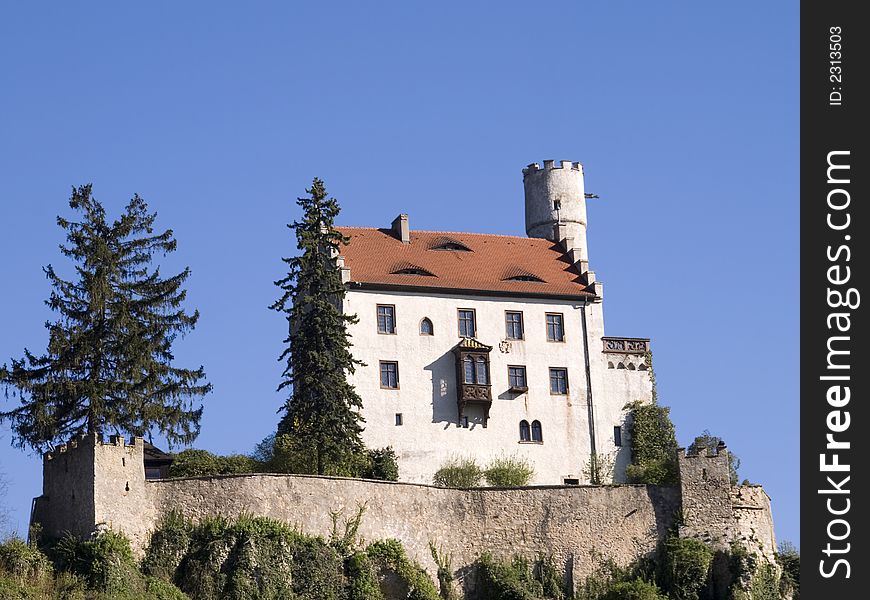 White castle with tower and main house in front of blue sky