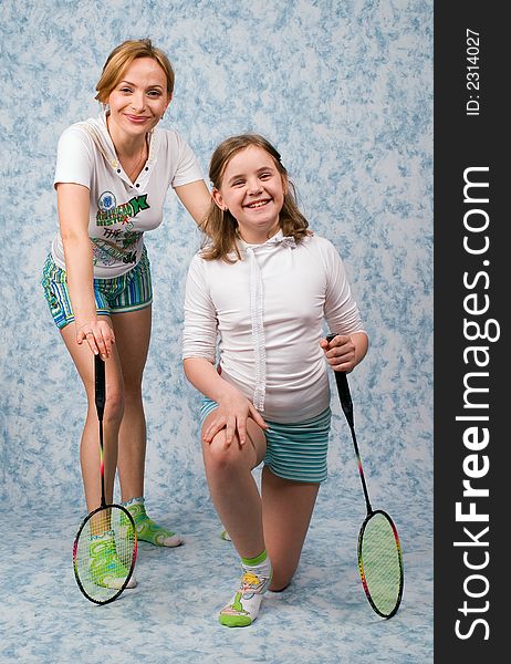 Mum and daughter play badminton on a blue background. Mum and daughter play badminton on a blue background