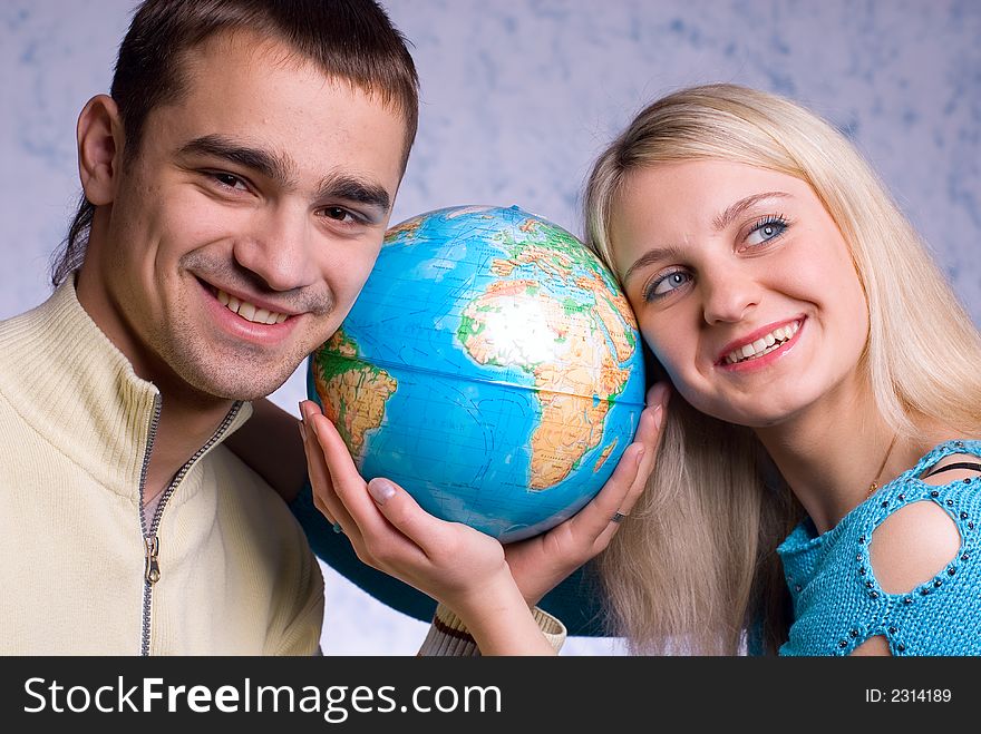 The guy and the girl hold the globe on a blue background