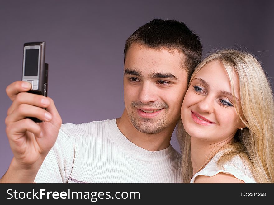 The guy and the girl with mobile phone on a grey background