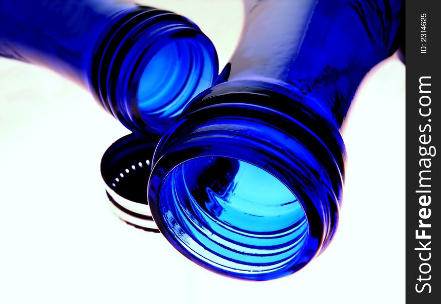 Two blue water bottles and a cap against a white background.