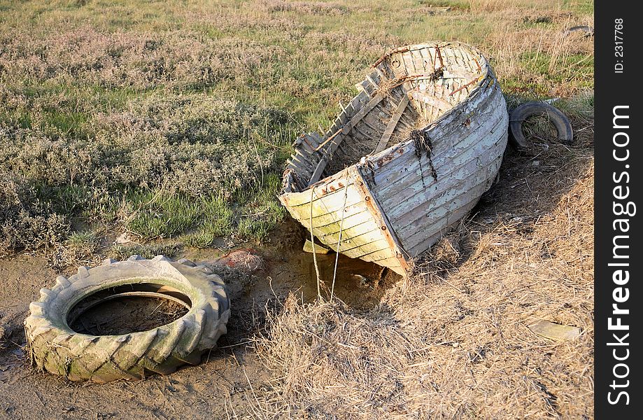 Rotten old rowing boat with tyre. Rotten old rowing boat with tyre