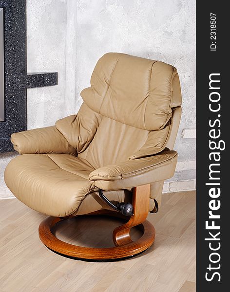 Modern leather arm chair with wooden stand near wall. Modern leather arm chair with wooden stand near wall