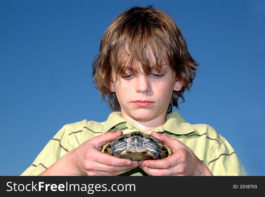 A boy outside gently holding a turtle, concerned about nature/environment. A boy outside gently holding a turtle, concerned about nature/environment