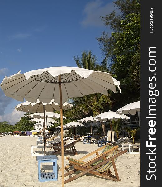 Chairs and white parasols on a tropical beach with white sand. Chairs and white parasols on a tropical beach with white sand