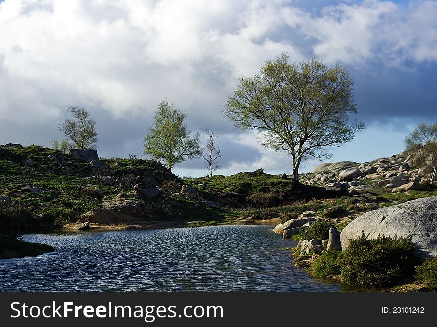 A small pond on the top of a mountain is ruffle by the wind. A small pond on the top of a mountain is ruffle by the wind.