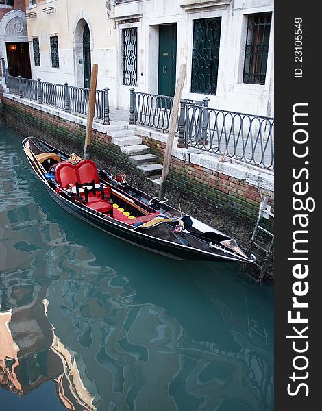 Empty gondola tied to building wall on a canal in Venice, Italy. Empty gondola tied to building wall on a canal in Venice, Italy