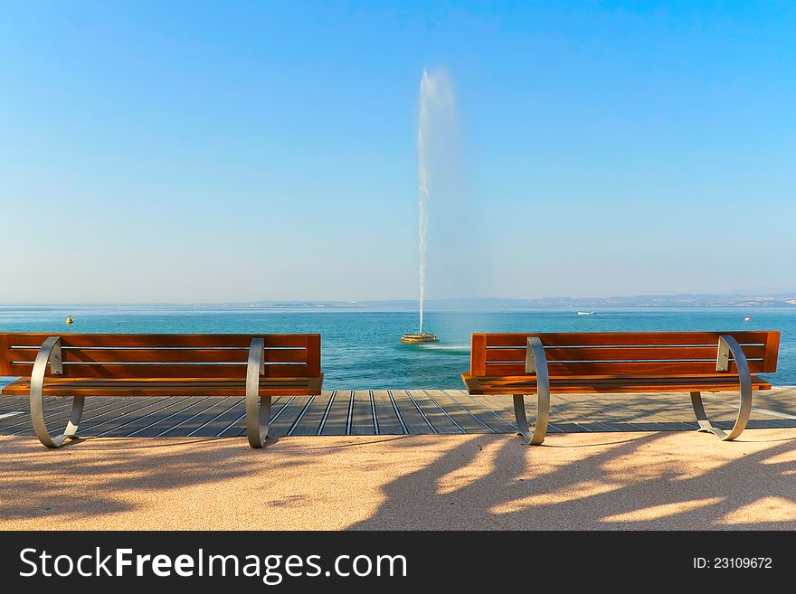 Modern benches along the coastline of Lake Garda. Benches and a fountain in the lake. (Bardolino,Italy)