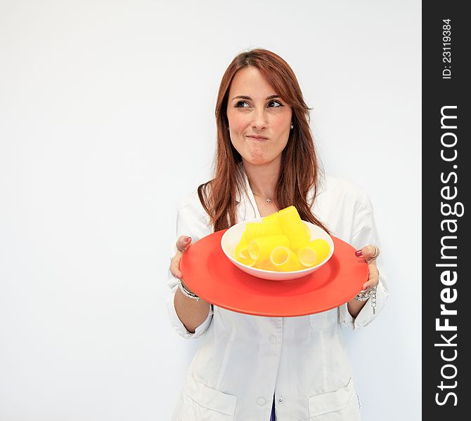 Beautiful woman doctor offering a dish of curlers instead of food for a fashion diet. Beautiful woman doctor offering a dish of curlers instead of food for a fashion diet