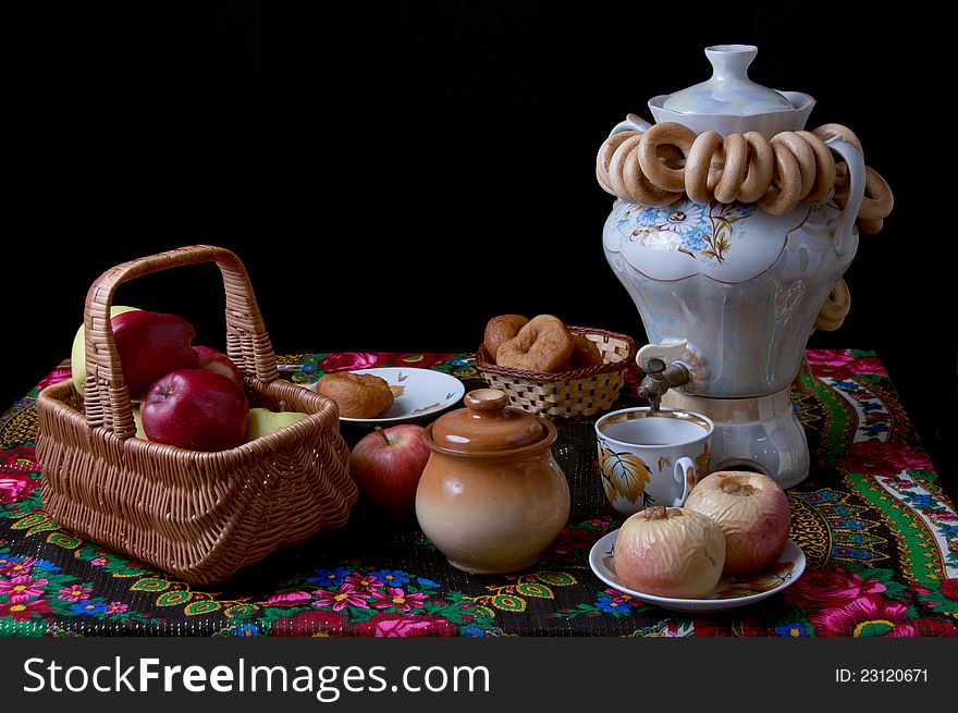 Samovar with bagels and apples on table over black. Samovar with bagels and apples on table over black