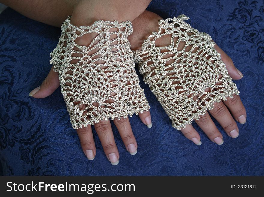 Hands of Alaska Native woman wearing fancy fingerless gloves made with crochet pineapple stitch design.