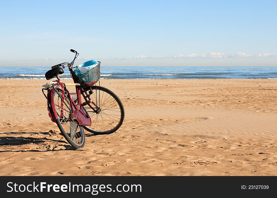 Bicycle with garbage can standing on beach against blue sky. Bicycle with garbage can standing on beach against blue sky