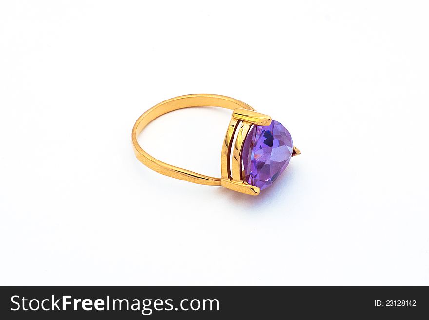 The brilliant gold ring with a stone lying on a white background.