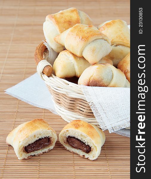 A basket of rolls with chocolate on a bamboo napkin