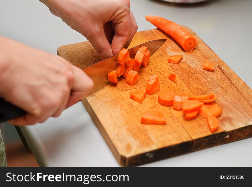 A chef preparing carrots for cooking by cutting them to small pieces. A chef preparing carrots for cooking by cutting them to small pieces.