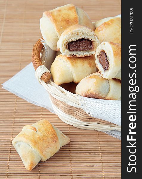 A basket of rolls with chocolate on a bamboo napkin