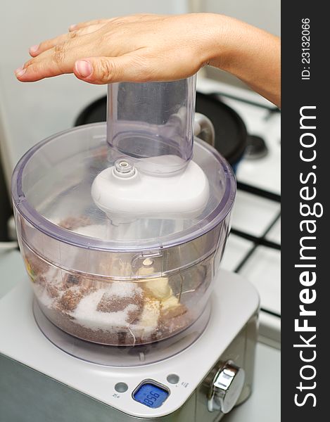 A chef mixing ingredients for a cake in a blender with hand on top. A chef mixing ingredients for a cake in a blender with hand on top.