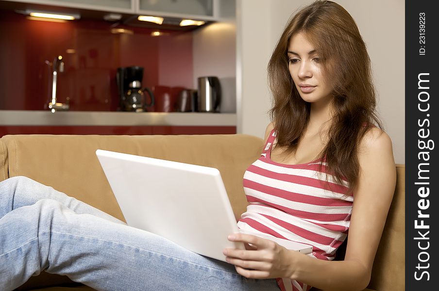 Young woman lying on a white sofa with a laptop.