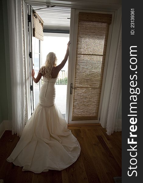 Vertical photograph of a bride posing in front of an open door. Vertical photograph of a bride posing in front of an open door