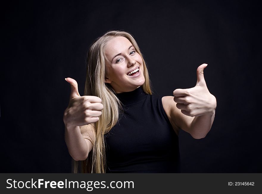 YOUNG FEMALE SHOWING A THUMBS UP ON BLACK. YOUNG FEMALE SHOWING A THUMBS UP ON BLACK