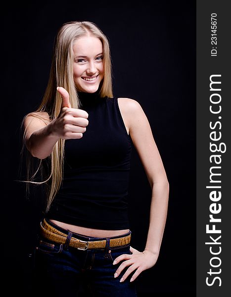 Smiling teenage girl showing thumbs up on black. Smiling teenage girl showing thumbs up on black