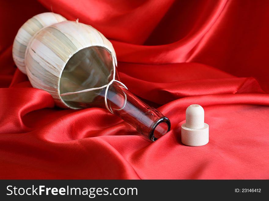 Empty bottle and cork on red silk surface