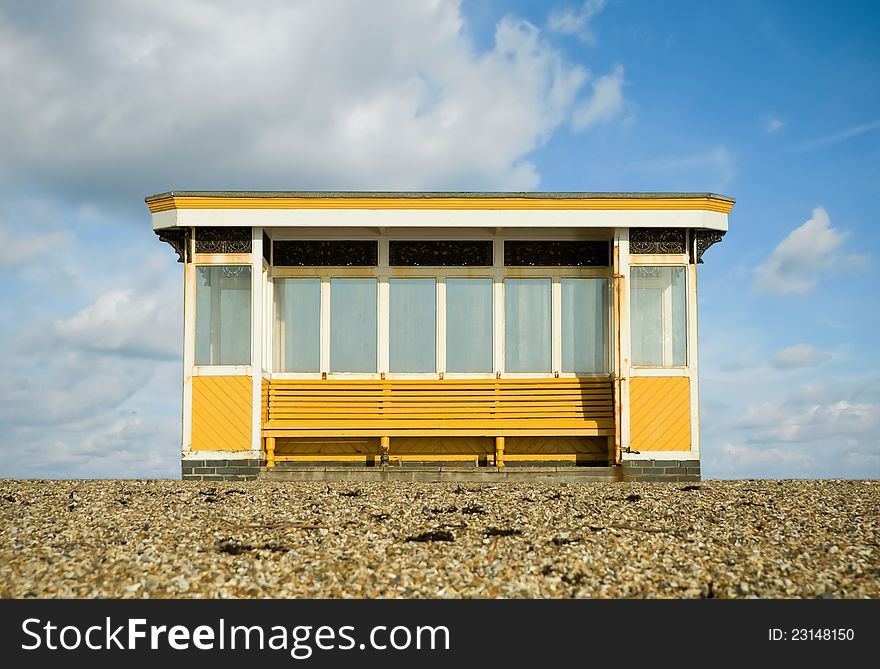 Weathered beach storm shelter against a blue cloudy sky