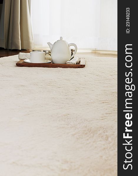 White color tea set on a carpet in a room. White color tea set on a carpet in a room