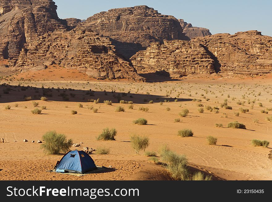 Lone tent in the Wadi Rum UNESCO World Heritage desert area. Long shadow from a towering peak.