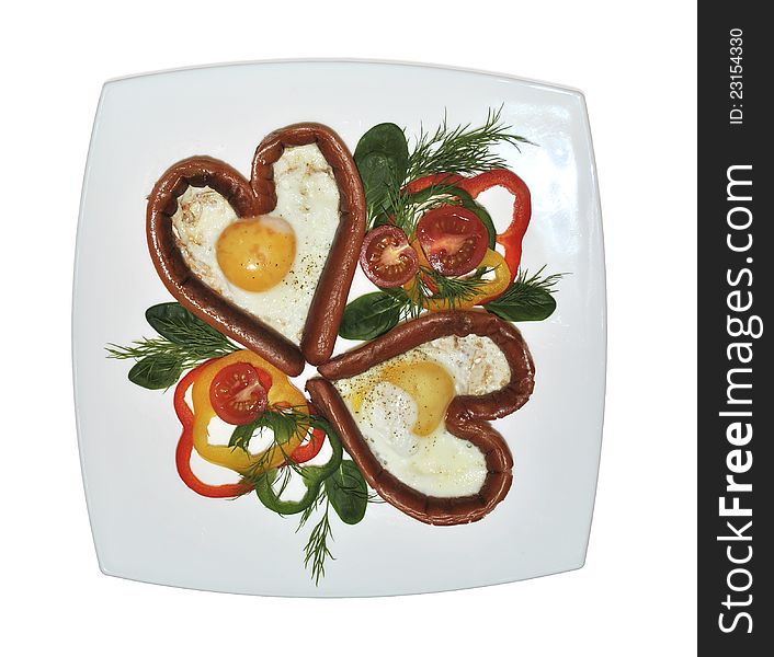 Valentines day breakfast - grilled heart-shaped sausages with eggs and slices of multi-colored peppers, cherry tomatoes and herbs