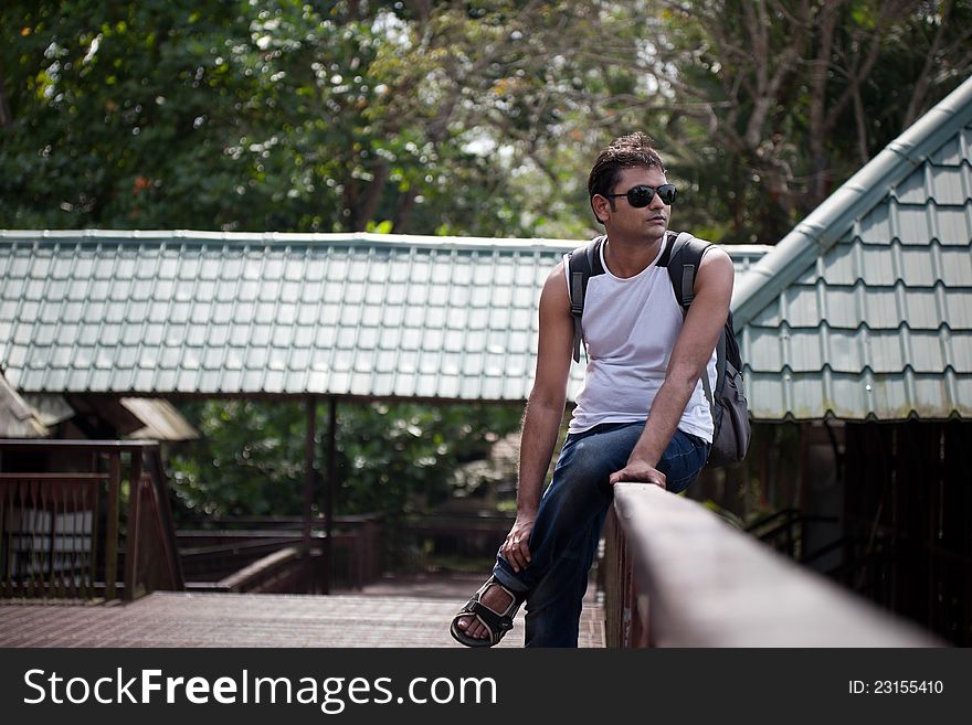 Happy indian man sitting on railing of house