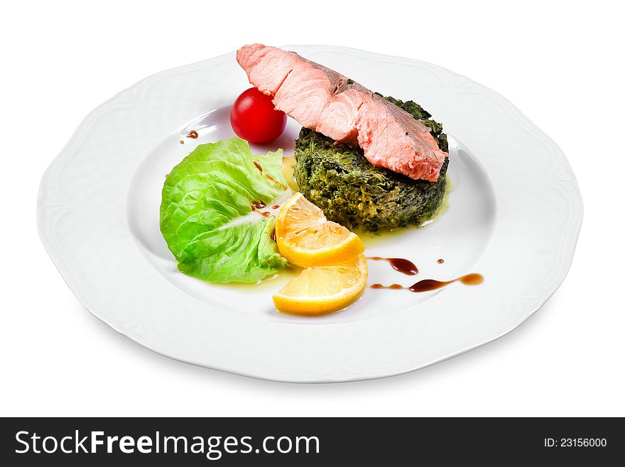 Salmon with spinach garnish, cherry tomato, lemon slices on a plate, on white