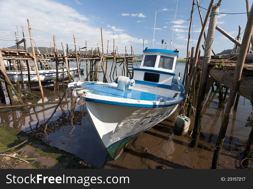 A blue white boat stay in a wood pier, in Asturias. A blue white boat stay in a wood pier, in Asturias