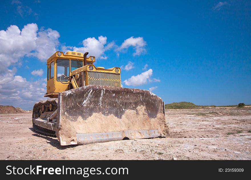 Orange bulldozer after the work is on a background of blue sky
