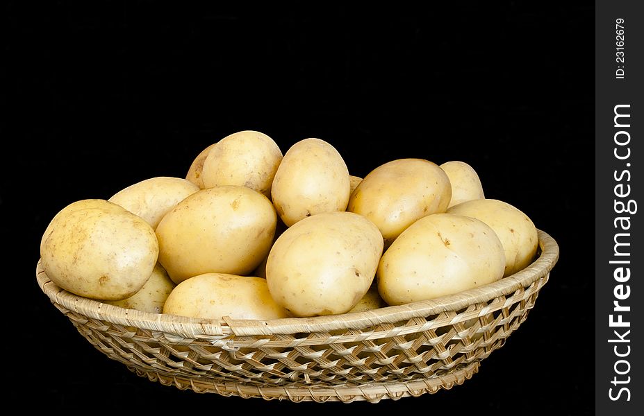 Potatoes in wicker bowl isolated on black background